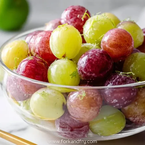 bowl of red and green grapes with lime zest on top in clear glass bowl
