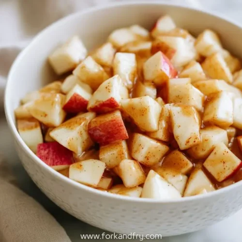 diced red apples coated in maple cinnamon glaze in a white bowl