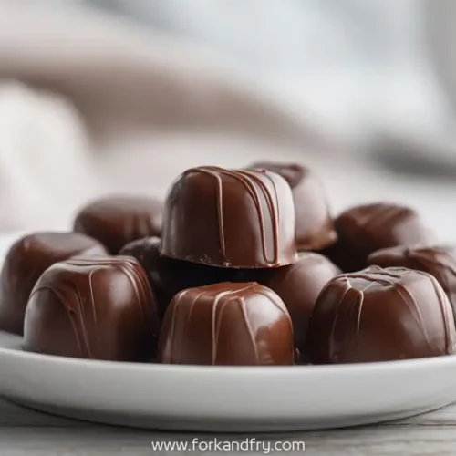 Stacked chocolate marshmallow cream candies with a glossy finish on a white plate