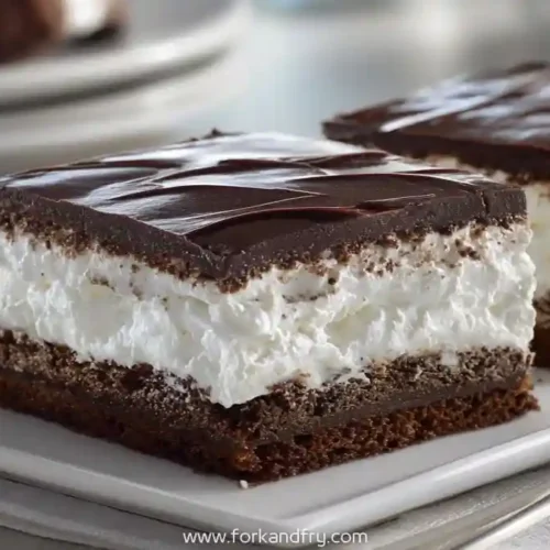 chocolate marshmallow cream bars with thick whipped filling and glossy ganache topping on a plate