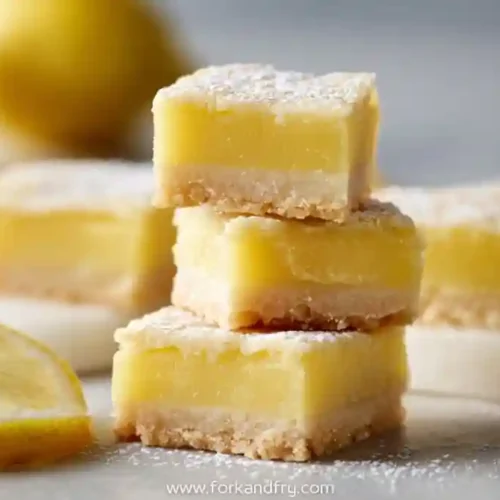 mini lemon bars with powdered sugar and buttery shortbread crust on marble tray