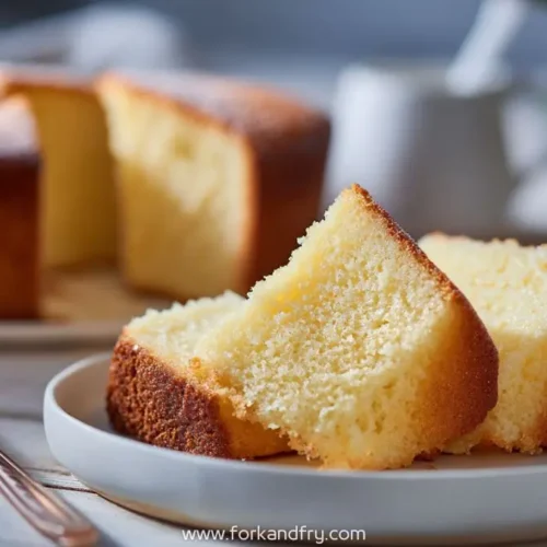 Two golden butter cake slices on a small plate in warm natural light with blurred cake in background