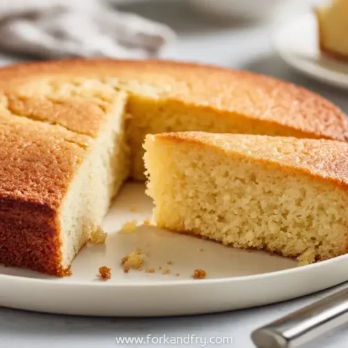 golden vanilla sponge cake slice on white plate with crumb texture
