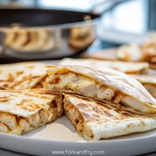 Crispy skillet chicken quesadillas stacked on a white plate with melted cheese