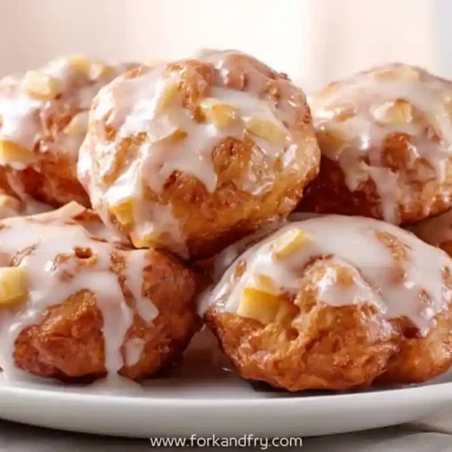 Plate of stacked baked apple fritters glazed with icing and apple chunks