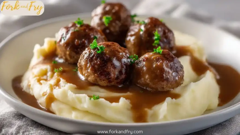 beef meatballs with brown gravy over creamy mashed potatoes garnished with parsley