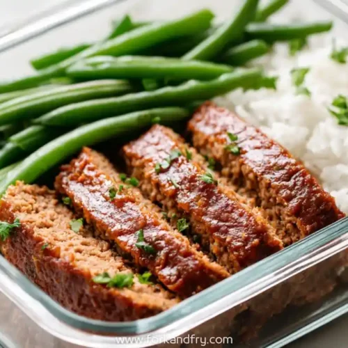 Glass meal prep container with sliced chicken meatloaf, green beans, and white rice