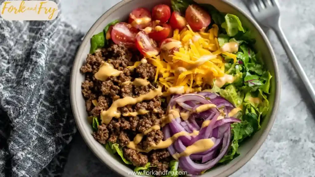 High-Protein Cheeseburger Bowls – Low-Carb Meal Prep with Ground Beef and Burger Sauce 7 High protein cheeseburger bowl with ground beef, cheddar cheese, cherry tomatoes, red onion, lettuce and creamy burger sauce