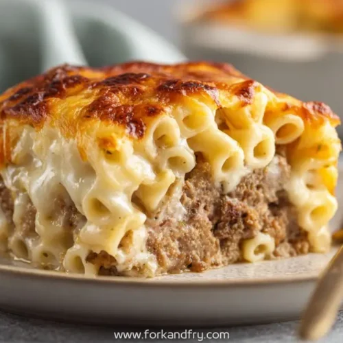 Slice of macaroni meatloaf bake with creamy cheese pasta layers on a plate