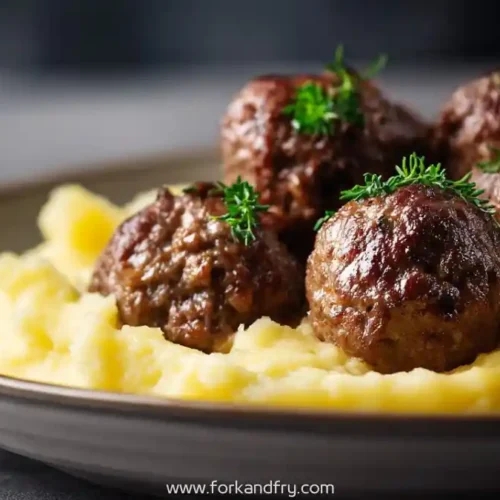 juicy beef meatballs on creamy mashed potatoes garnished with fresh herbs