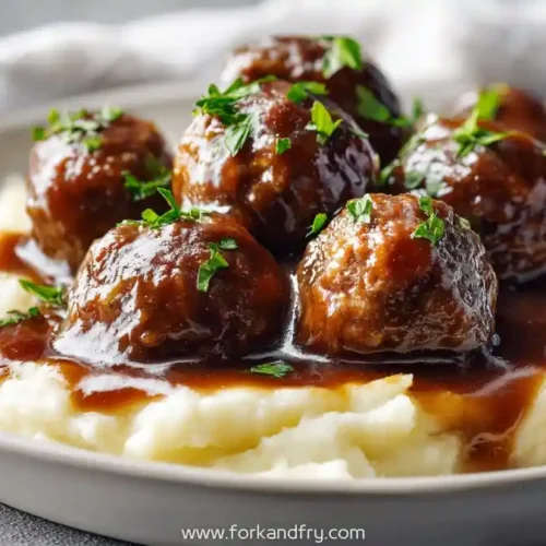 salisbury steak meatballs with brown gravy over mashed potatoes on plate