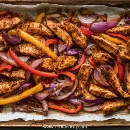 Sheet pan chicken fajitas with bell peppers and red onions roasted on baking tray