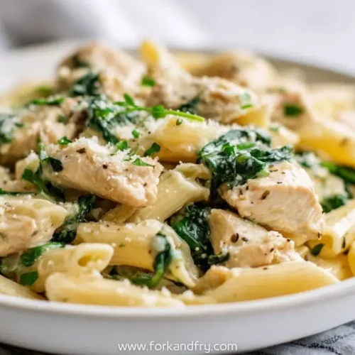 Creamy spring chicken pasta with spinach and parmesan in white bowl
