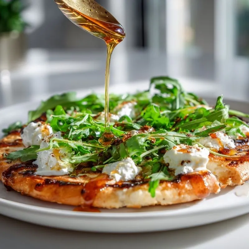 Sweet and Savory Arugula Cheese Flatbread with Honey Drizzle Grilled flatbread topped with arugula, soft cheese, and golden honey drizzle