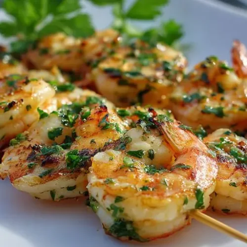 garlic grilled shrimp skewers with herbs and charred edges served on white plate