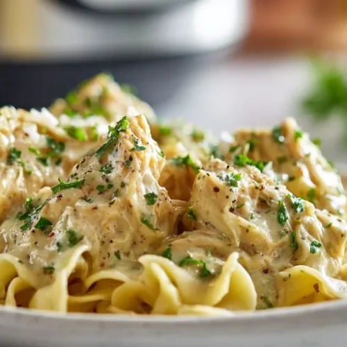 Creamy Crockpot Ranch Chicken in a rich ranch sauce served over buttery egg noodles and garnished with fresh parsley.