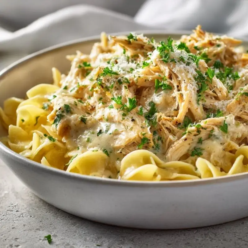 Creamy Crockpot Ranch Chicken Over Egg Noodles Creamy Crockpot Ranch Chicken served over buttered egg noodles with parsley and grated Parmesan in a shallow bowl.