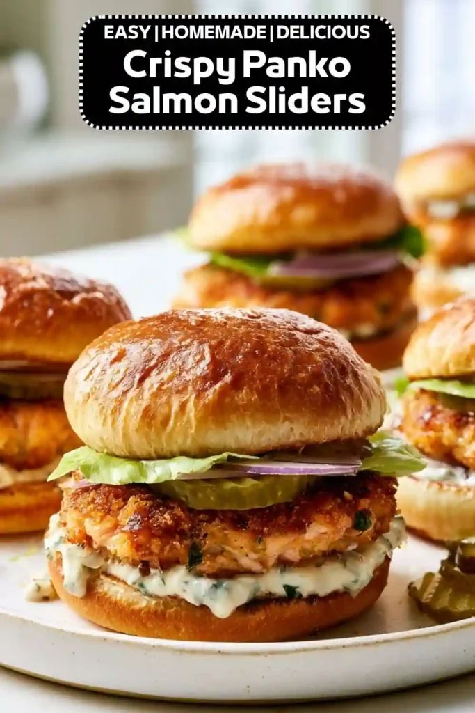 Crispy panko salmon sliders with homemade salmon patties, lettuce, pickles, red onion, and creamy herb sauce on toasted brioche buns.